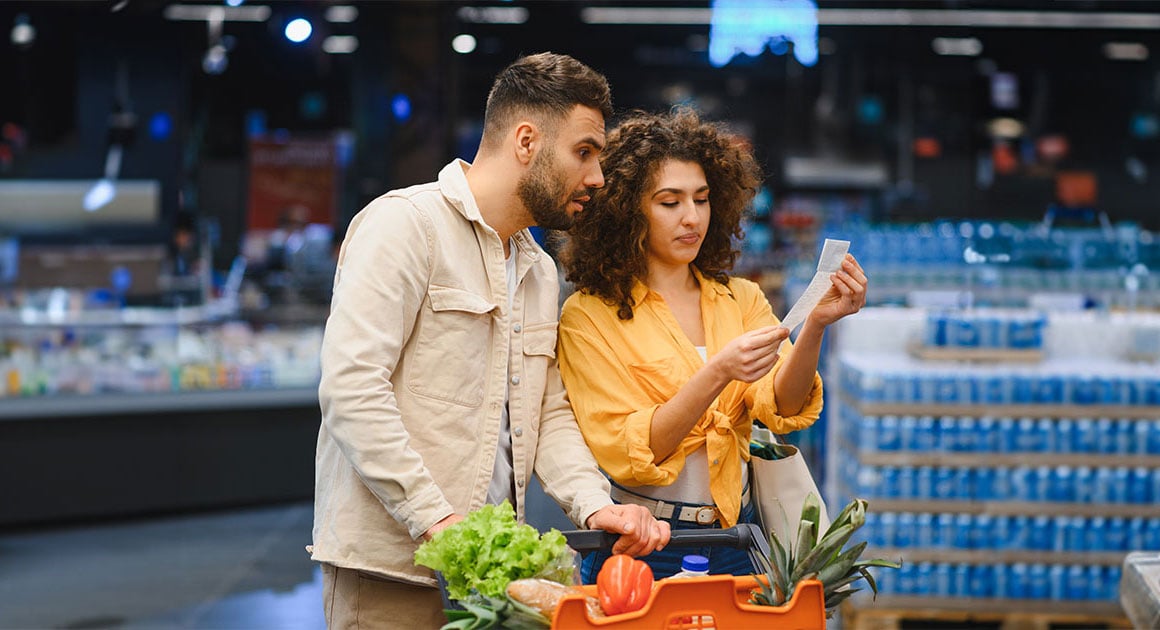man and woman looking at receipt in grocery store