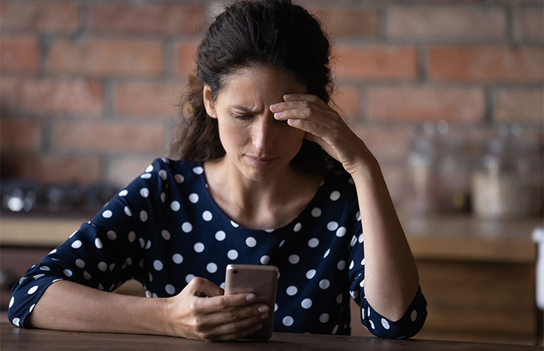 woman with concerned expression looking at phone