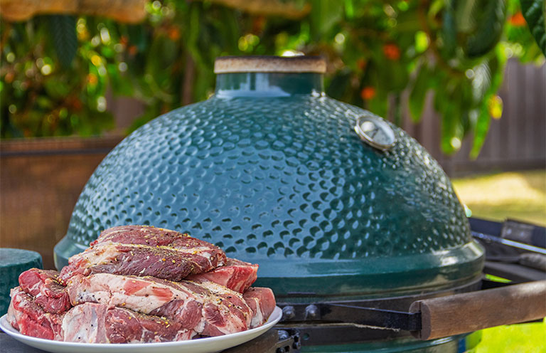 raw seasoned steaks in front of grill