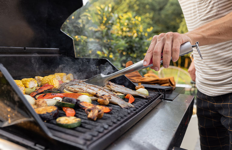 man grilling fish and vegetables