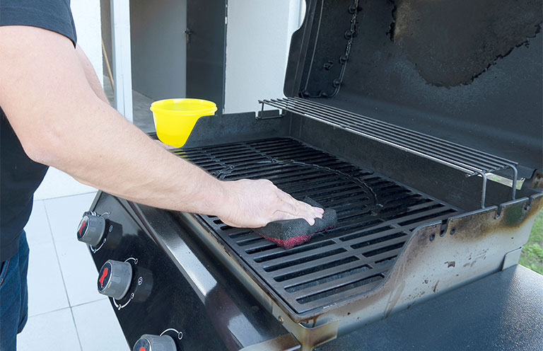 man cleaning grill