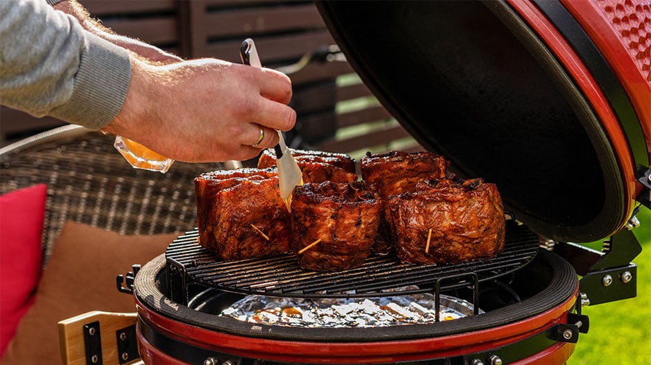 man adding sauce to meat on grill