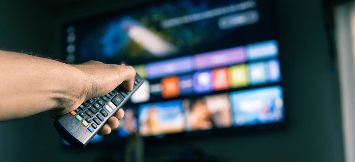 remote in hand, blurred background, tv with apps