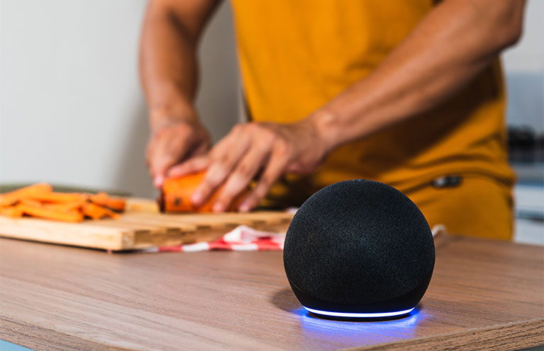 AI speaker on while person chopping carrots in background
