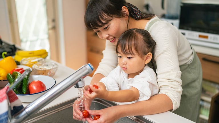 A mother is helping her small daughter washing vegetables and encouraging her for healthy eating. Credit: recep-bg
