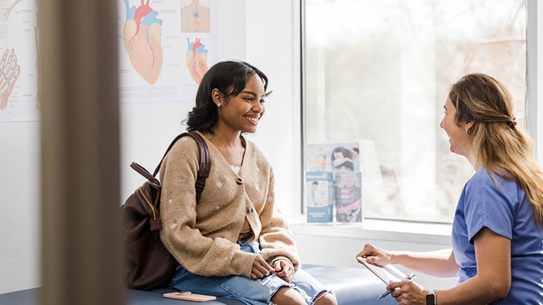 The young adult female patient smiles while listening to the nurse give an encouraging update regarding her medical exam that was recently completed. Credit: SDI Productions