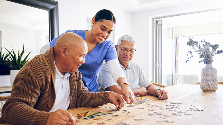 Puzzle, caregiver and senior men playing a game as entertainment or bonding together in a retirement home. Happy, fun and elderly people enjoy mental rehabilitation and development with nurse Credit: Jacob Wackerhausen