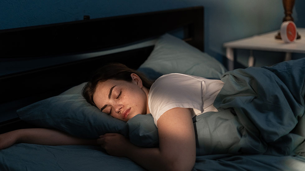 Young female sleeping peacefully in her bedroom at night. Relaxing at nighttime. Credit: Andrii Lysenko