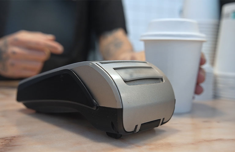 card reader on counter next to cup of coffee