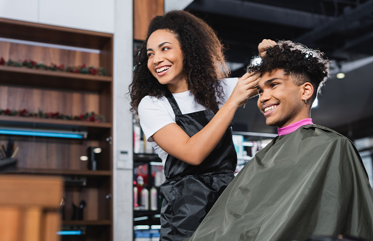 woman smiling and giving man a haircut