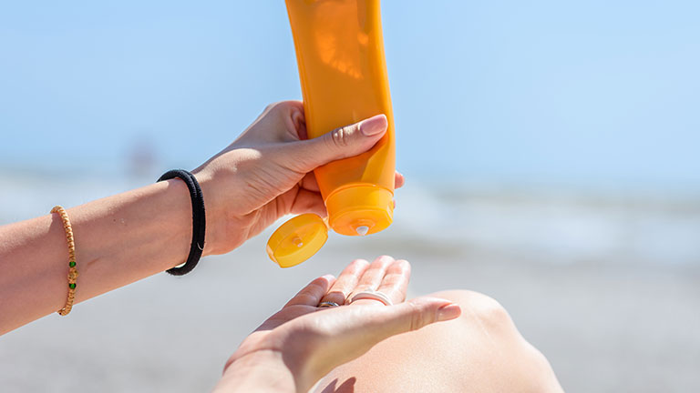 A woman holding bottles of sunscreen in her hands. Close-up.; Credit: O_Lypa