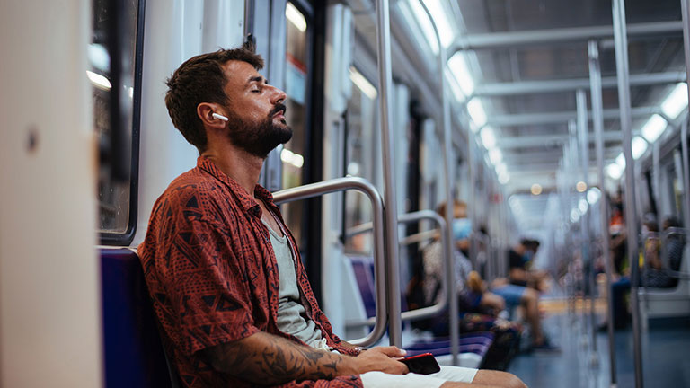 Young man listening to music on his headphones and resting while sitting on a subway train Credit:mihailomilovanovic