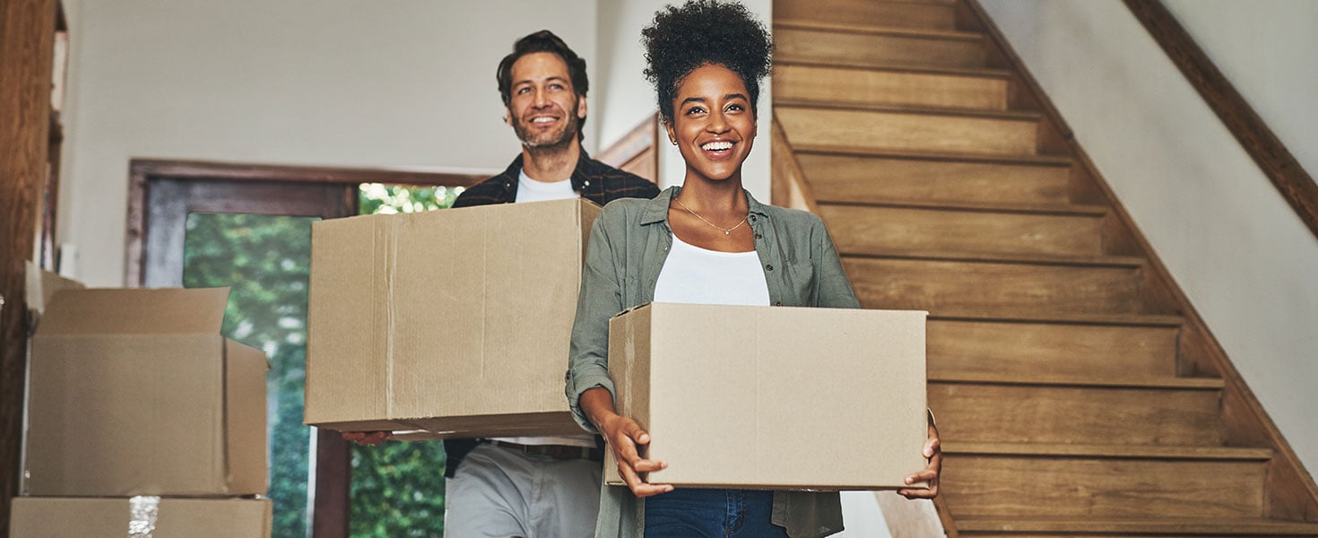 Happy couple, real estate and moving in new home with boxes for renovation, investment or relocation. Interracial man and woman owner carrying box for property rent, mortgage loan or move together. by A. Frank/peopleimages.com