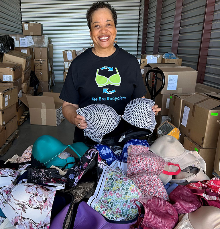Elaine Birks Mitchell CEO of The Bra Recyclers with piles of donated bras