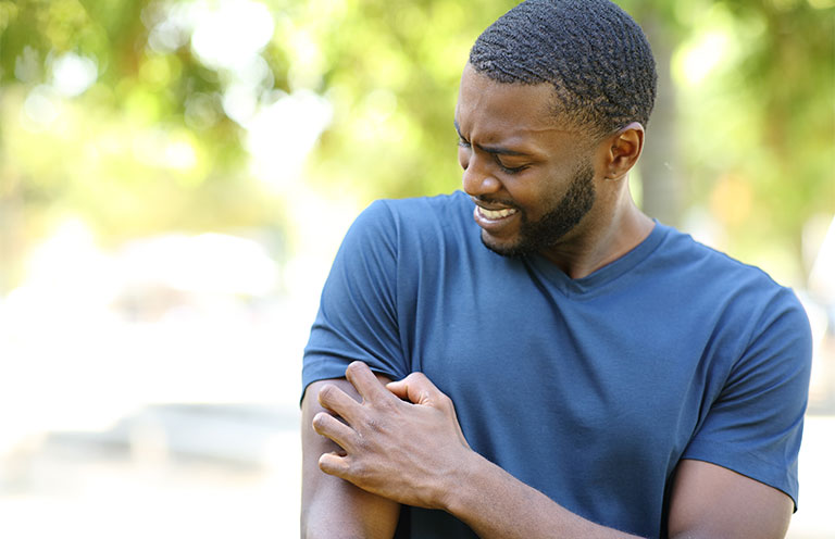 man scratching itch on arm