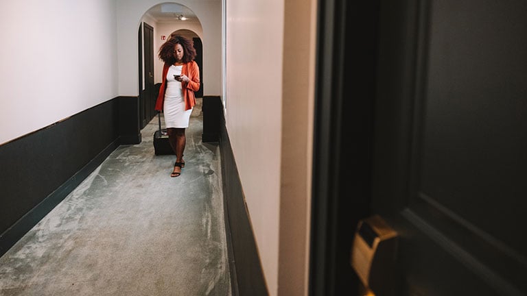 A shot of a young receptionist talking to three tourists standing behind the counter inside a hotel in Niseko, Japan. Credit: halbergman