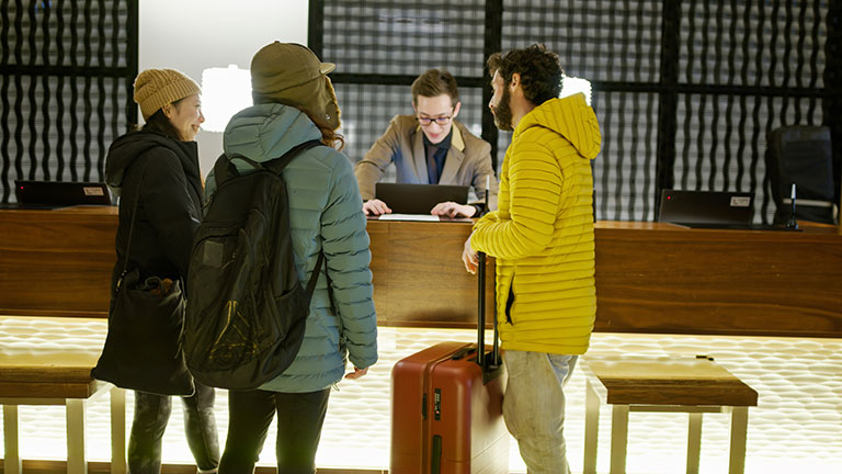 Businesswoman texting on mobile in a hotel corridor; Credit: LeoPatrizi