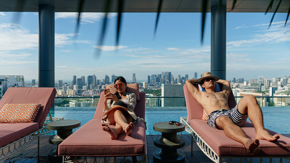 Asian couple on holiday basking under the sun by the poolside