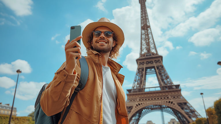 Tourist taking a selfie in front of the Eiffel Tower in Paris; By acnaleksy