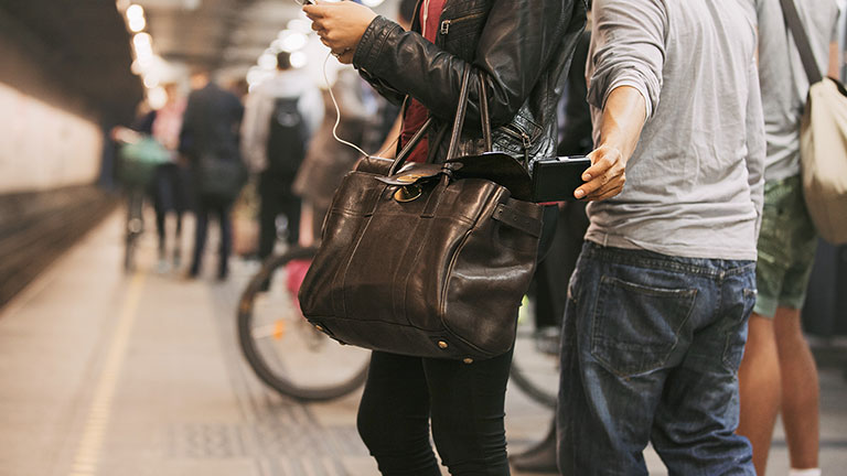 Thief stealing wallet from purse of a woman using mobile phone at the subway station. Pickpocketing at subway station.  Credit: jacoblund
