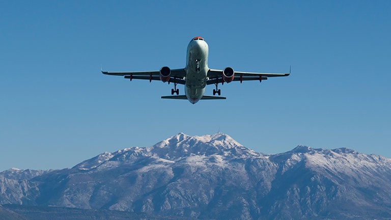 The plane is landing at the airport against the background of mountains in the snow By scharfsinn86