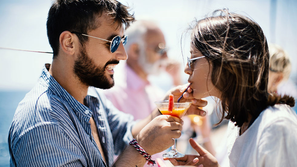 man holding cocktail for woman on cruise ship