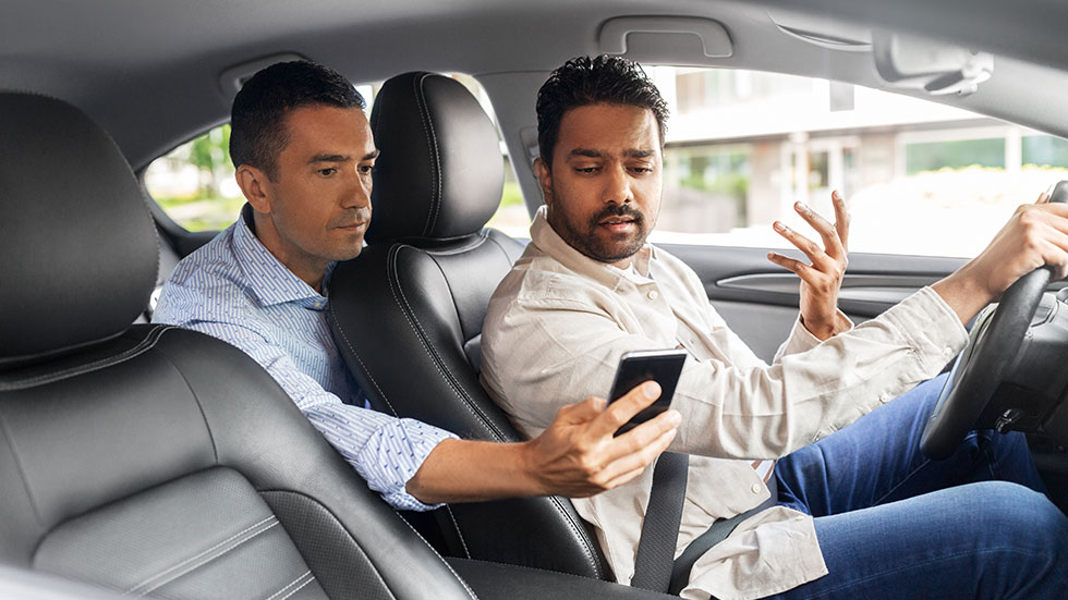 Downloaded transportation, vehicle and technology concept - male passenger showing smartphone to car driver; by Syda Productions