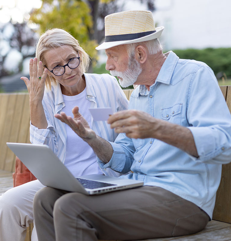 Elderly couple excitedly handling an online payment outdoors