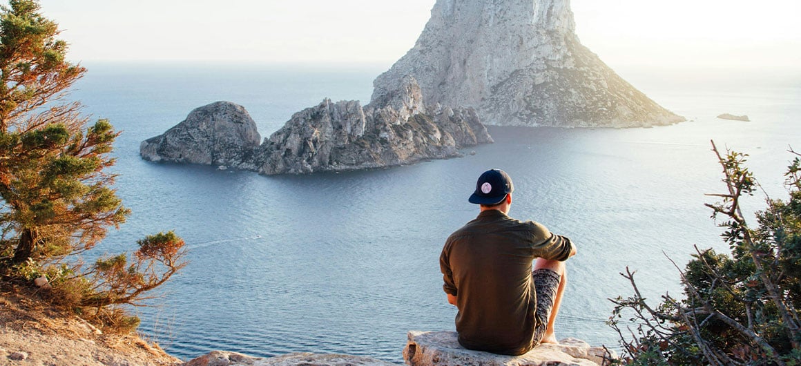 man sitting at cliff looking at view