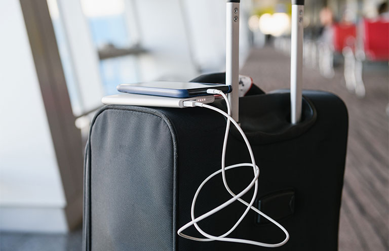 phone charging with portable charger laying on top of carryon suitcase