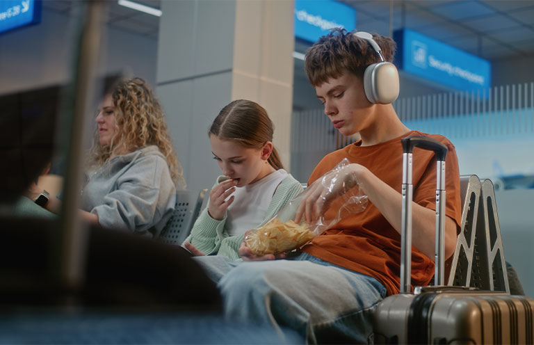 boy and girl sitting in airport eating chips