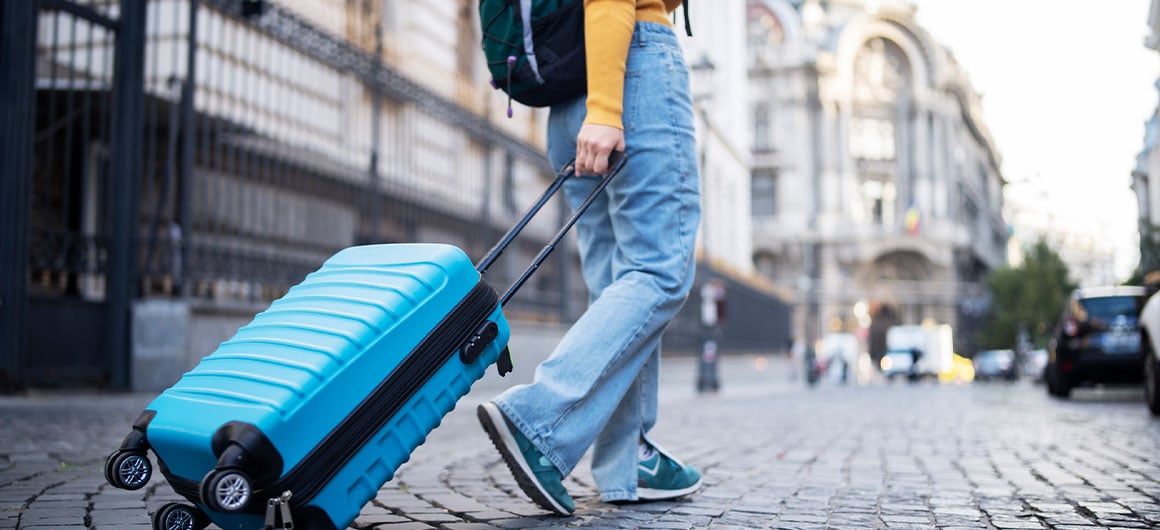 woman carrying on suitcase on cobblestone road