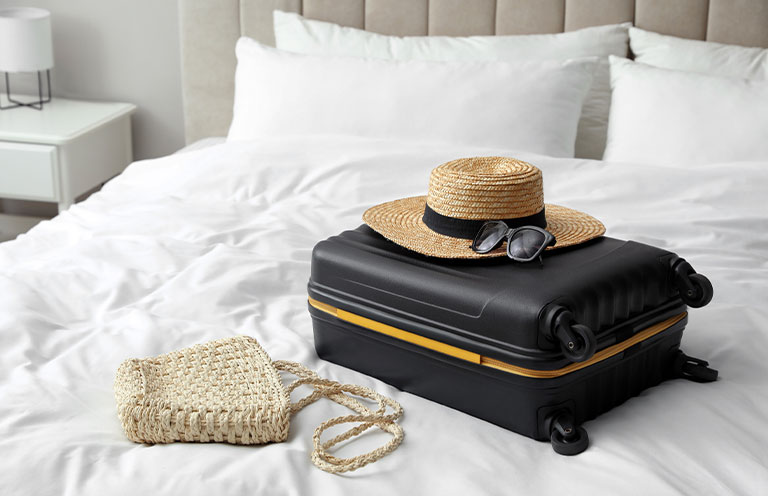 suitcase, hat, and bag on bed