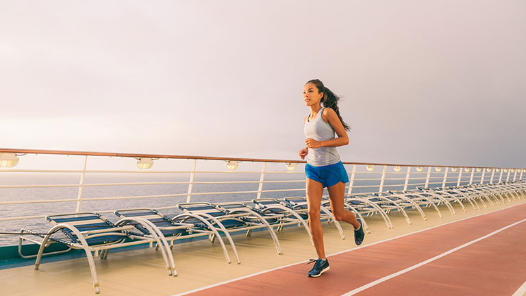 Cruise ship fitness workout run people lifestyle. Woman doing exercise on running track during Caribbean vacation. By Maridav