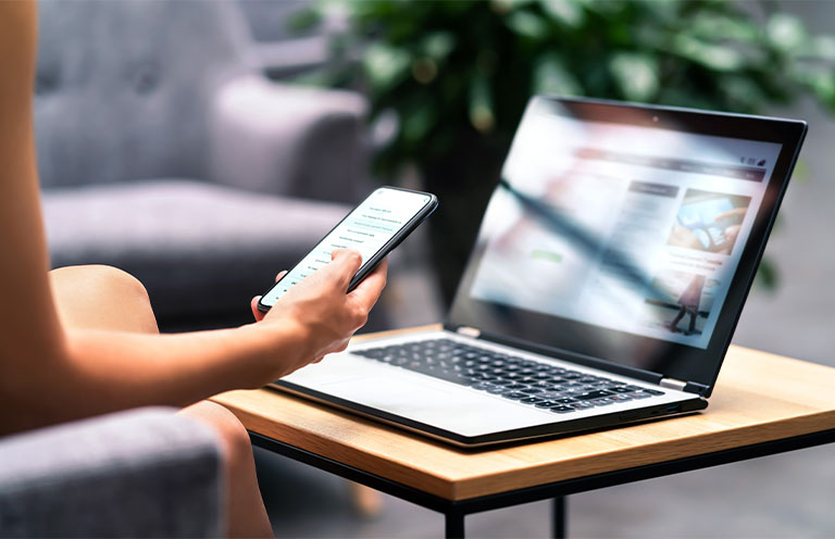 person using phone and laptop