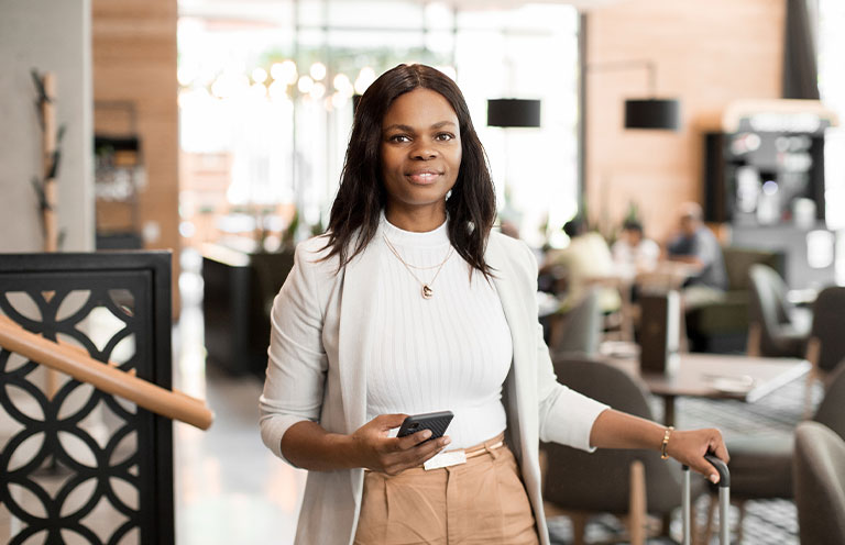 woman holding phone and suitcase handle
