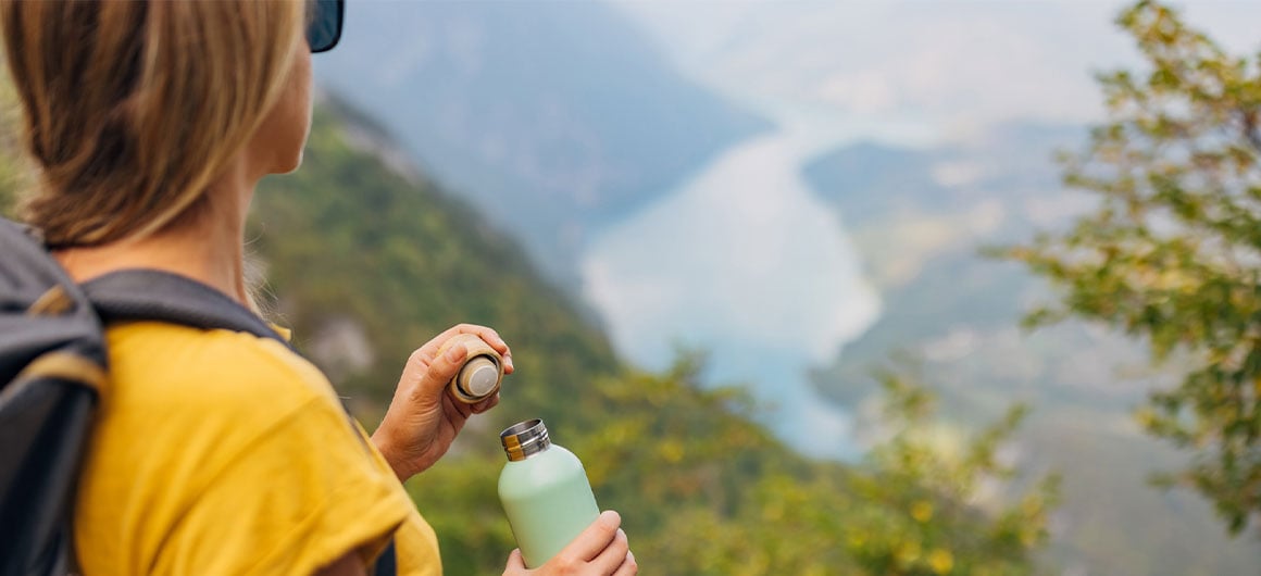 woman holding reusable water bottle and admiring view