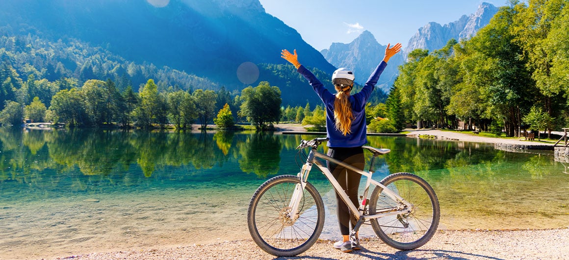 woman with arms raised enjoying beautiful emerald lake in Slovenia