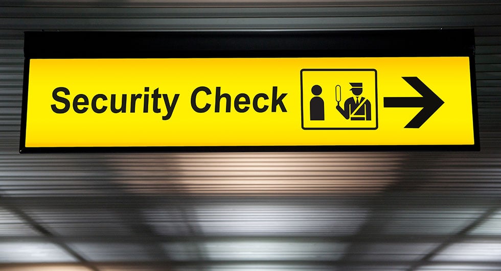 security check sign hanging from airport terminal ceiling