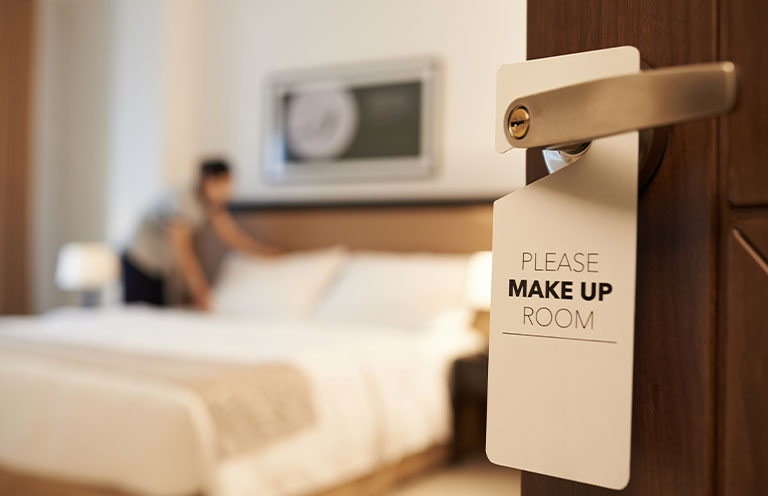door with a sign that says please make up room, woman in the room making bad