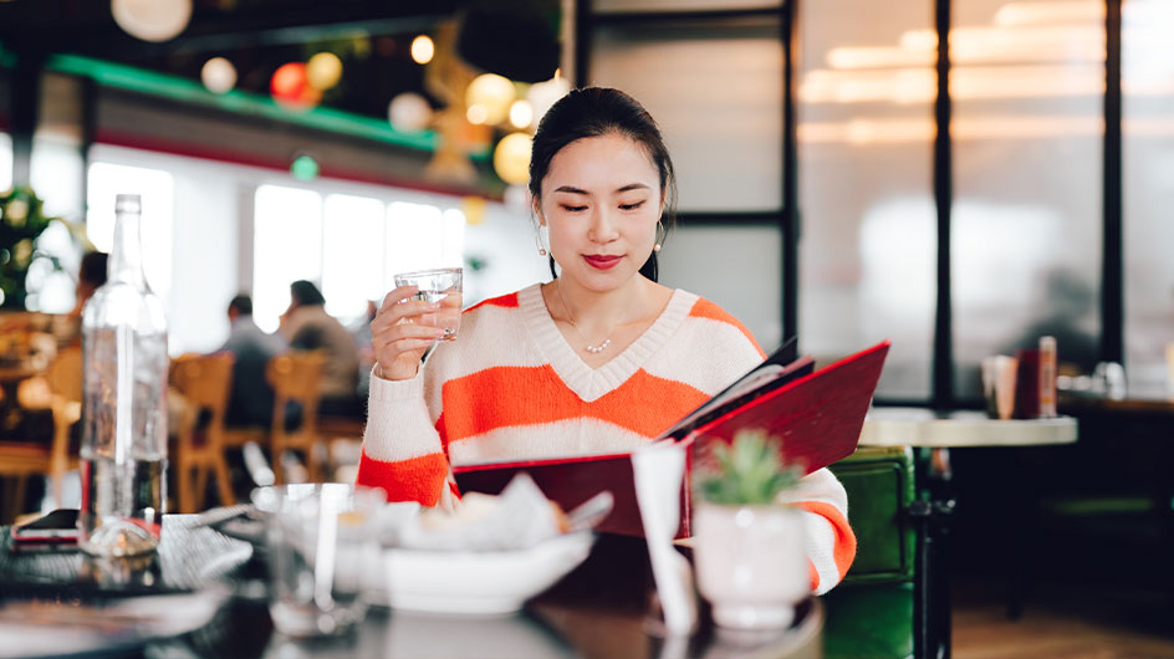 woman sitting at restaurant looking at menu