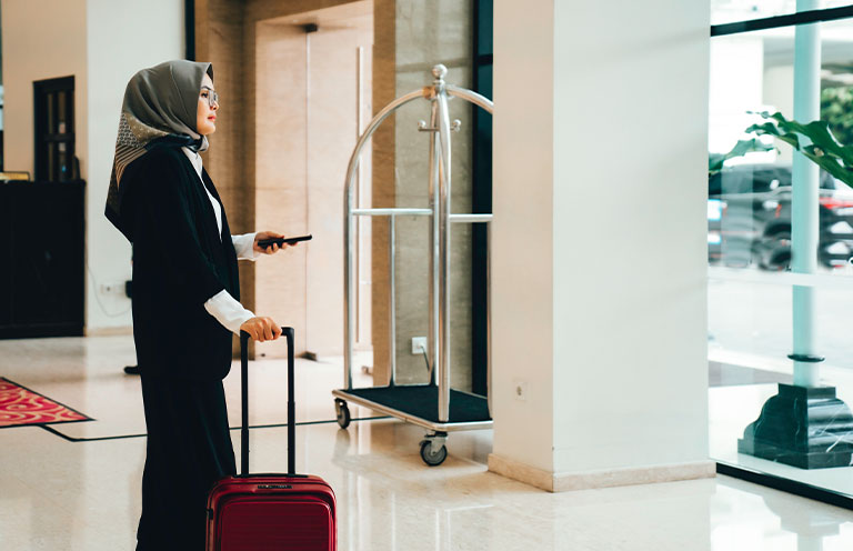 woman holding suitcase and phone in hand
