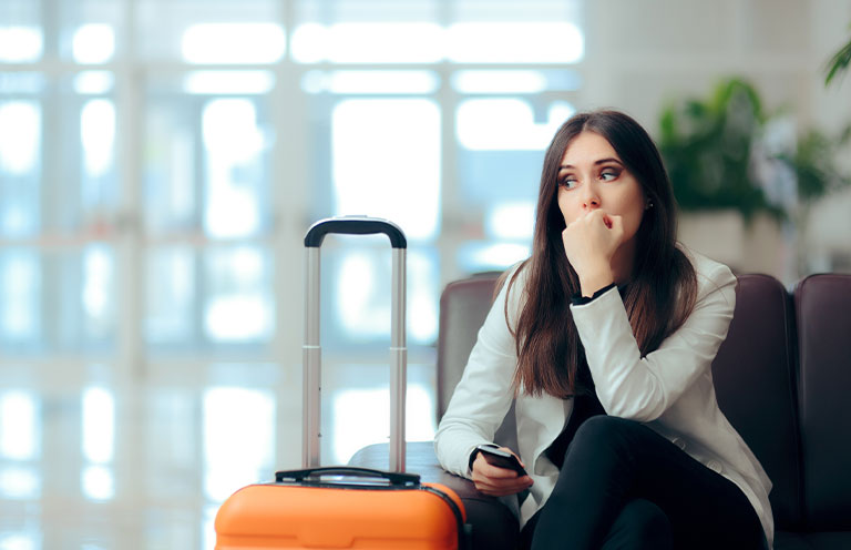woman sitting with suitcase, holding phone