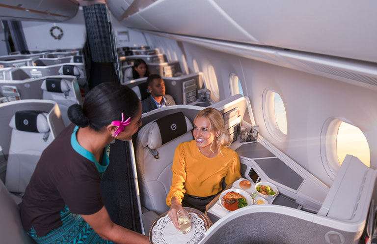 flight attendant on Fiji Airlines serving meal to customer