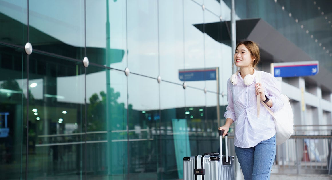 woman walking in airport with suitcase in hand