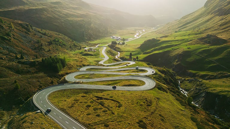 Scenic aerial view of serpentine road (Majola Pass) in mountains in autumn with traffic on it. Credit:Oleh_Slobodeniuk