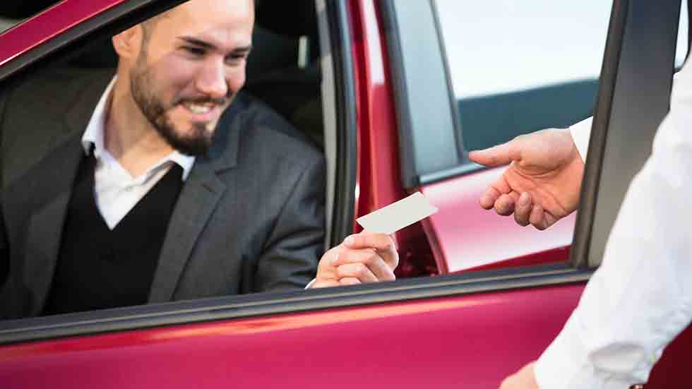 Valet Giving Receipt To Businessperson Sitting Inside Car