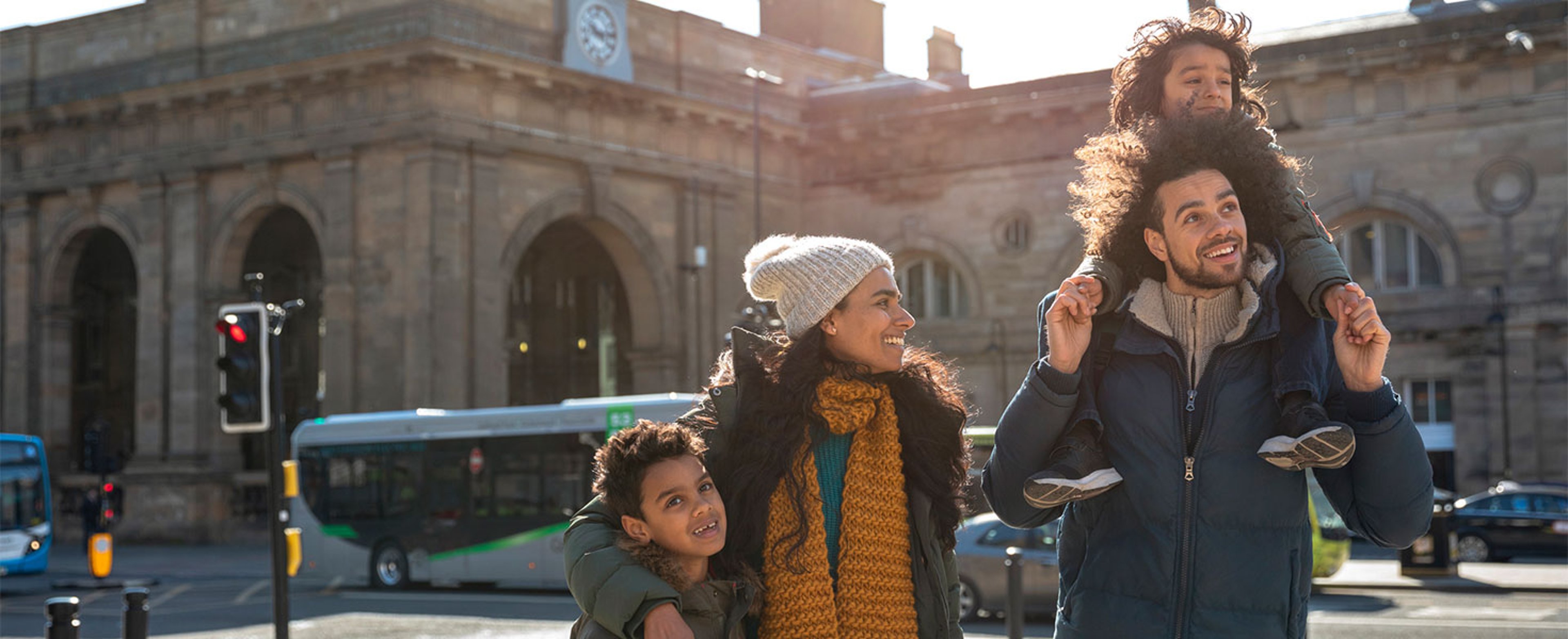 family walking in front of building and busses