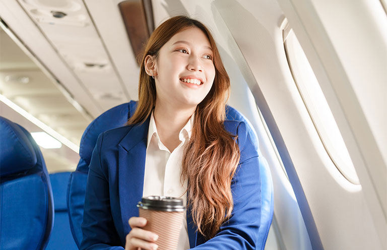 woman holding coffee looking out plane window