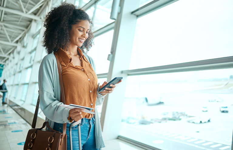 woman looking at phone while standing in airport